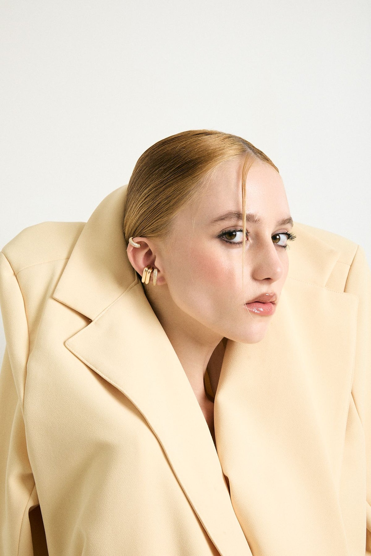 Model in a camel coat wearing the Harmony ear cuff set by By Odara